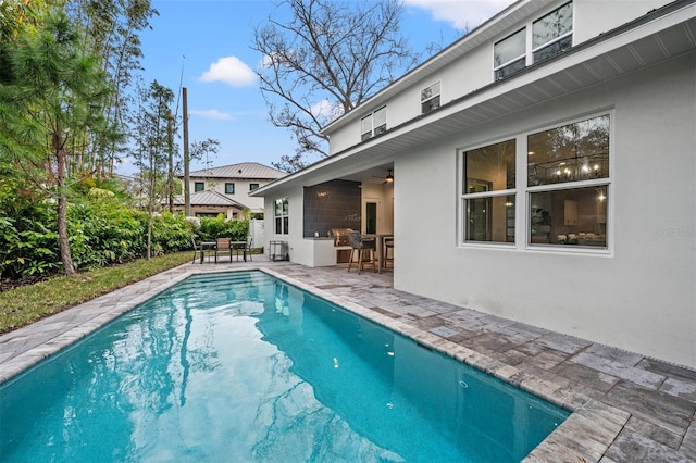 view of swimming pool with ceiling fan, an outdoor bar, and a patio