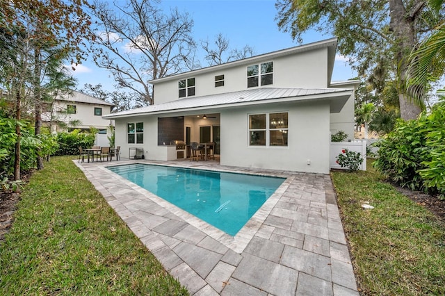 rear view of property featuring ceiling fan, a patio, and a lawn