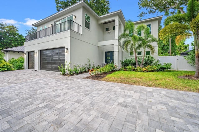 contemporary home featuring a garage, a front yard, and a balcony