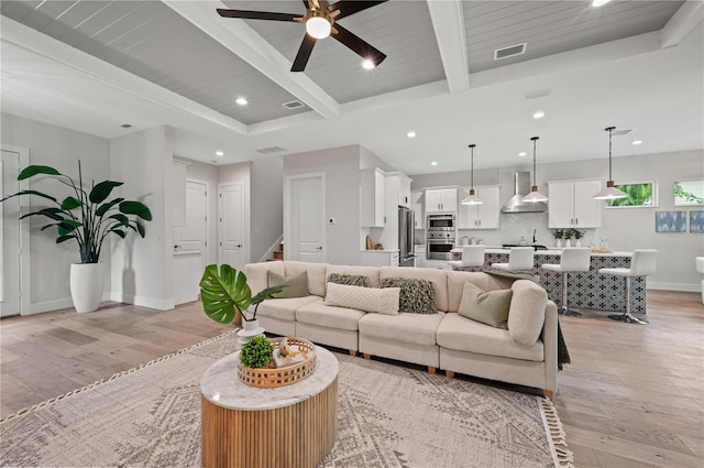 living room featuring sink, ceiling fan, light hardwood / wood-style floors, wooden ceiling, and beam ceiling