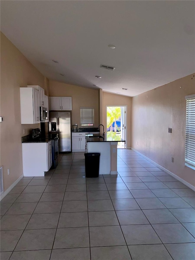 kitchen featuring white cabinets, light tile patterned flooring, lofted ceiling, and appliances with stainless steel finishes