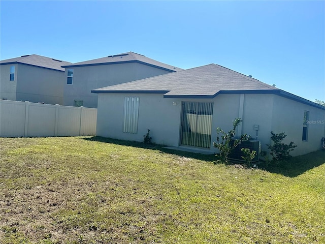 back of property featuring a lawn and central AC