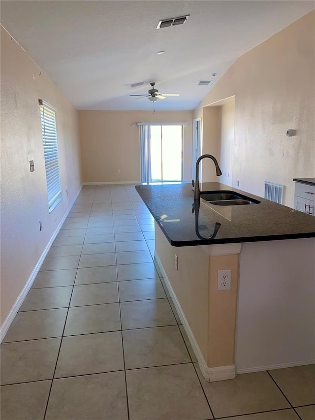 kitchen with sink, light tile patterned floors, lofted ceiling, and a center island with sink