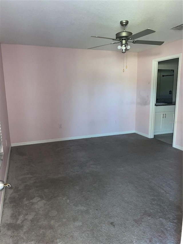 unfurnished room with ceiling fan and dark carpet