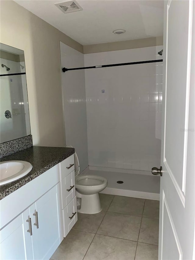 bathroom featuring tile patterned floors, vanity, toilet, and tiled shower