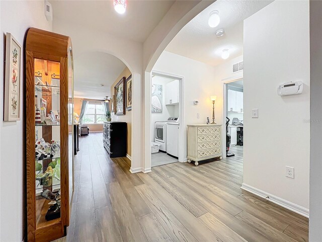 corridor featuring light wood-type flooring and independent washer and dryer