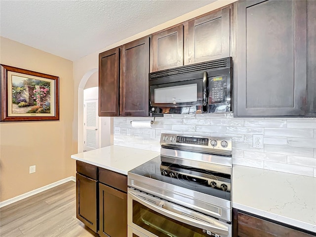 kitchen featuring light wood-type flooring, light stone counters, dark brown cabinets, a textured ceiling, and stainless steel electric range