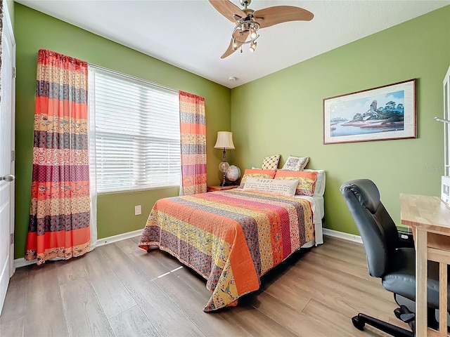 bedroom featuring multiple windows, wood-type flooring, and ceiling fan