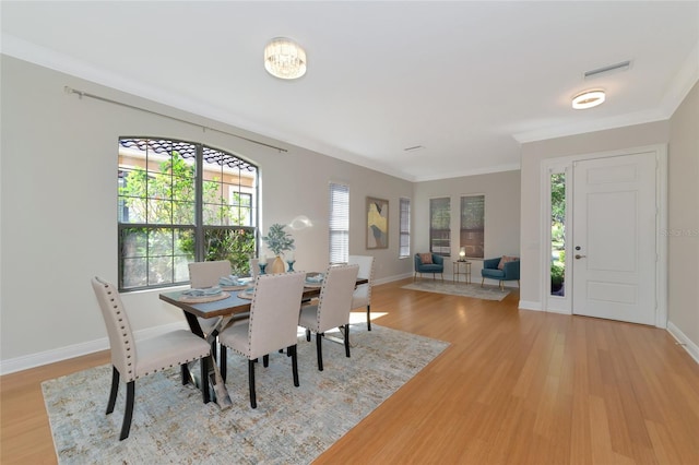 dining space with light wood-type flooring and crown molding