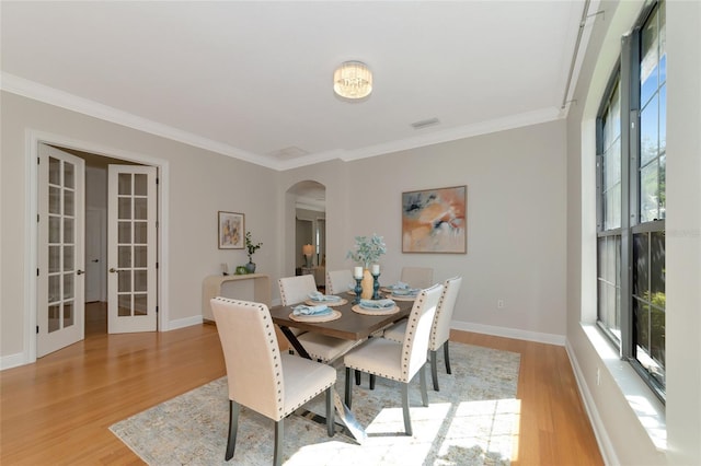 dining room featuring french doors, light hardwood / wood-style flooring, and ornamental molding