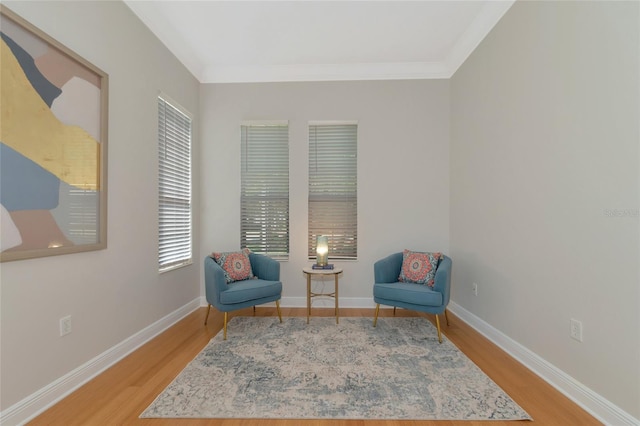 sitting room with light wood-type flooring and crown molding