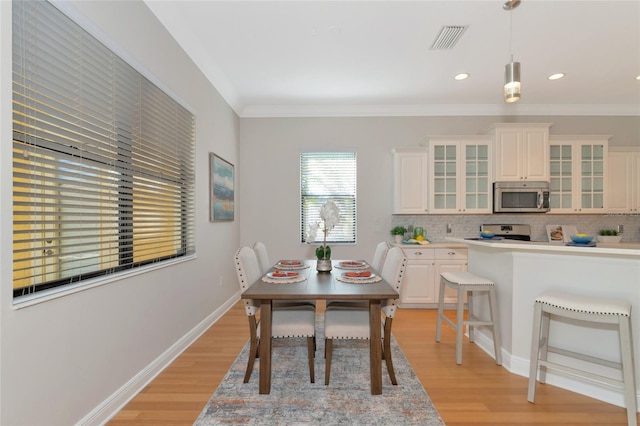 dining area with light hardwood / wood-style flooring and ornamental molding