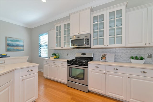 kitchen featuring crown molding, light wood-type flooring, white cabinetry, and stainless steel appliances