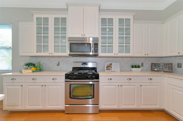 kitchen featuring light wood-type flooring, stainless steel appliances, white cabinetry, and crown molding