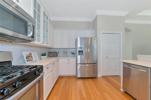 kitchen with decorative backsplash, light hardwood / wood-style flooring, white cabinets, and stainless steel appliances