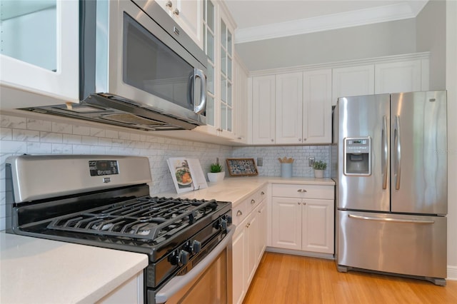 kitchen with stainless steel appliances, white cabinetry, tasteful backsplash, and light hardwood / wood-style flooring