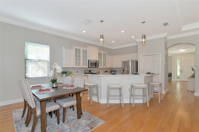 kitchen featuring decorative light fixtures, decorative backsplash, appliances with stainless steel finishes, and light hardwood / wood-style flooring