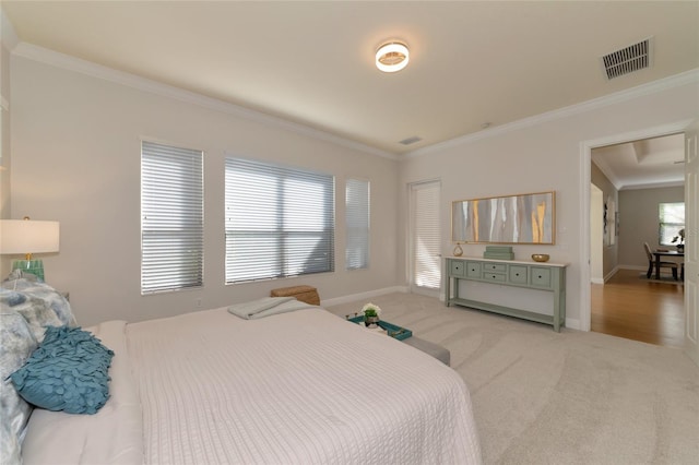 bedroom with ornamental molding and light carpet