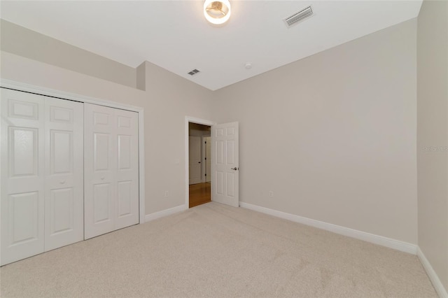 unfurnished bedroom with a closet and light colored carpet