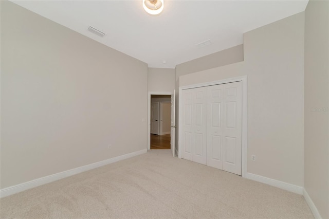 unfurnished bedroom featuring light colored carpet and a closet