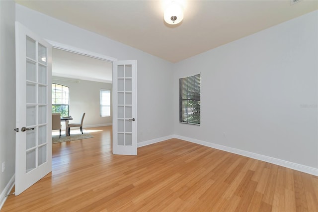 spare room with french doors and light hardwood / wood-style flooring