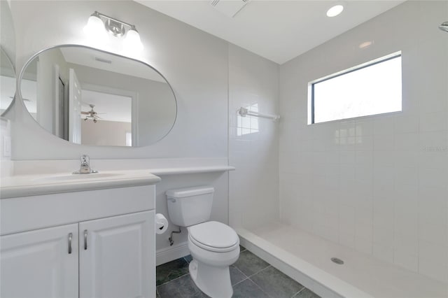 bathroom with tile patterned floors, a tile shower, vanity, ceiling fan, and toilet