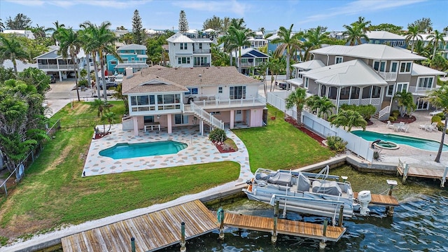 rear view of property featuring a yard, a water view, a fenced in pool, and a patio