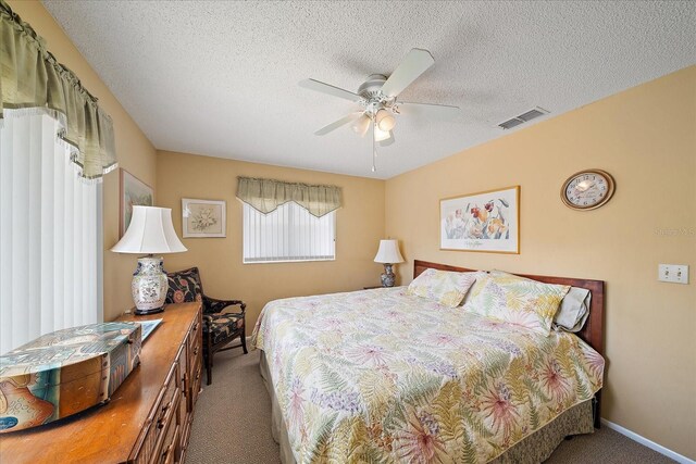 carpeted bedroom featuring ceiling fan and a textured ceiling