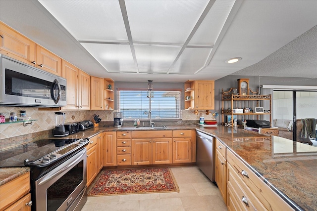 kitchen with dark stone counters, tasteful backsplash, light tile flooring, sink, and appliances with stainless steel finishes