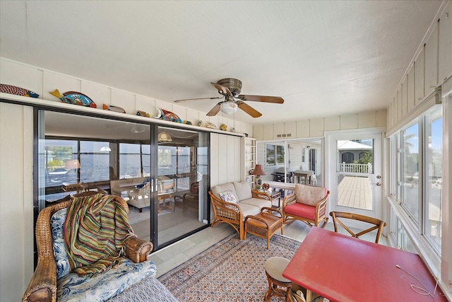 sunroom with a water view and ceiling fan