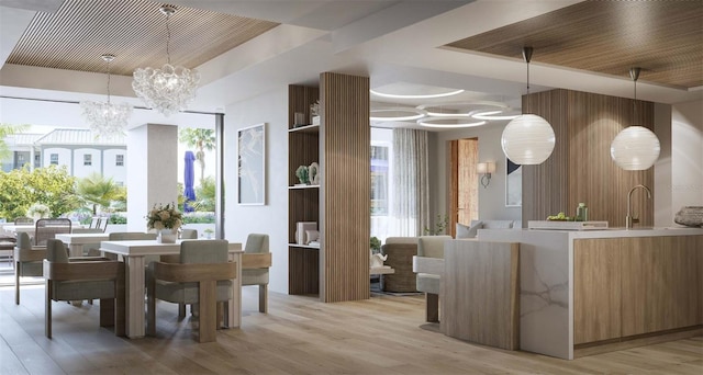 dining space with a notable chandelier, sink, light hardwood / wood-style floors, and a healthy amount of sunlight