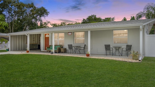 back house at dusk featuring a yard