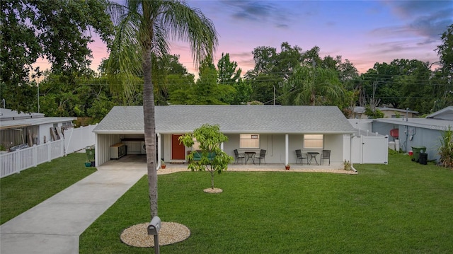 ranch-style house featuring a carport, a patio area, and a lawn