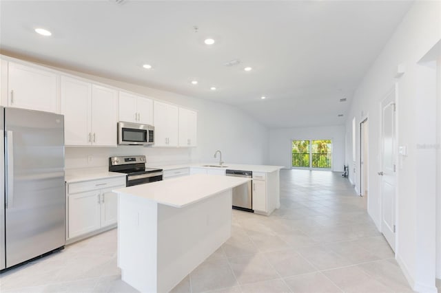 kitchen with kitchen peninsula, sink, white cabinets, lofted ceiling, and stainless steel appliances