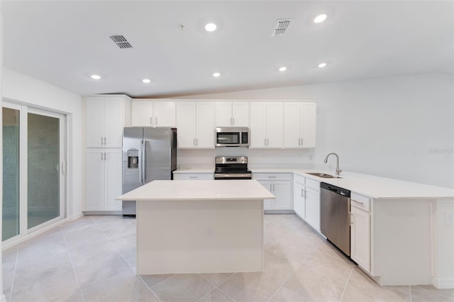 kitchen featuring white cabinets, appliances with stainless steel finishes, lofted ceiling, a kitchen island, and sink