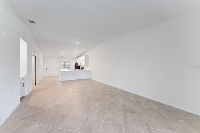 unfurnished living room featuring vaulted ceiling and light tile patterned floors