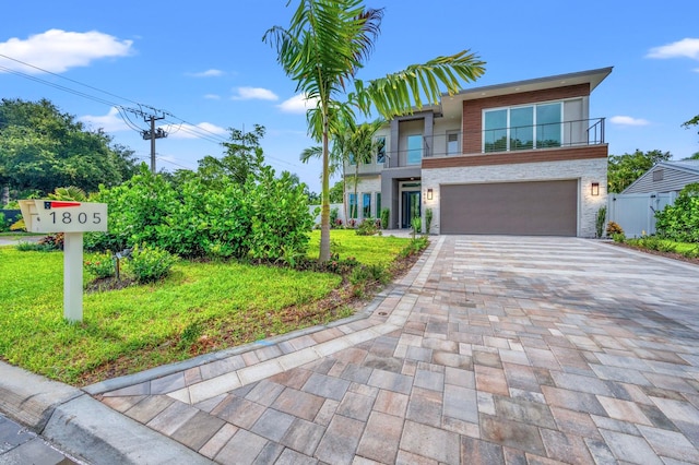 view of front of property with a balcony, a garage, and a front lawn