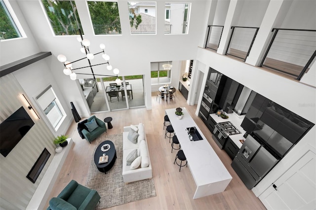 living room with a notable chandelier, light hardwood / wood-style floors, and a towering ceiling