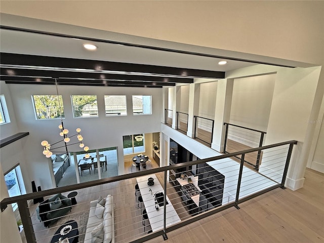 corridor with beam ceiling, a chandelier, and hardwood / wood-style flooring