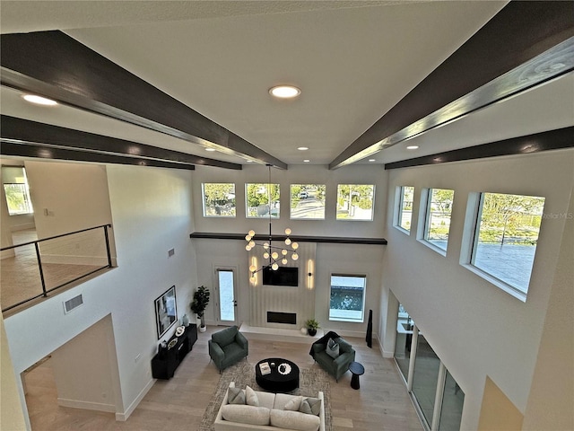 living room with a wealth of natural light, a notable chandelier, and light wood-type flooring