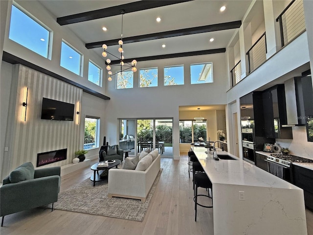 living room featuring a towering ceiling, a large fireplace, light hardwood / wood-style flooring, and sink