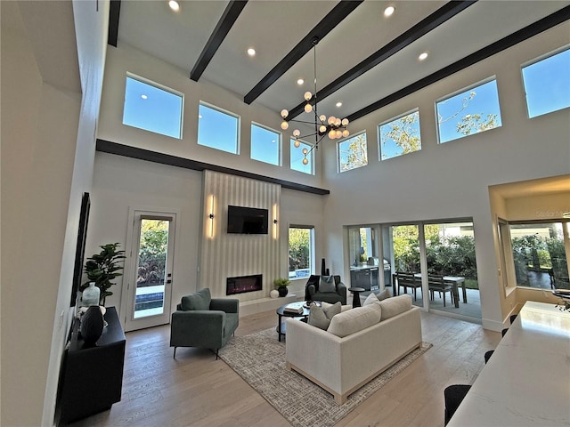 living room with beamed ceiling, plenty of natural light, a towering ceiling, and a notable chandelier