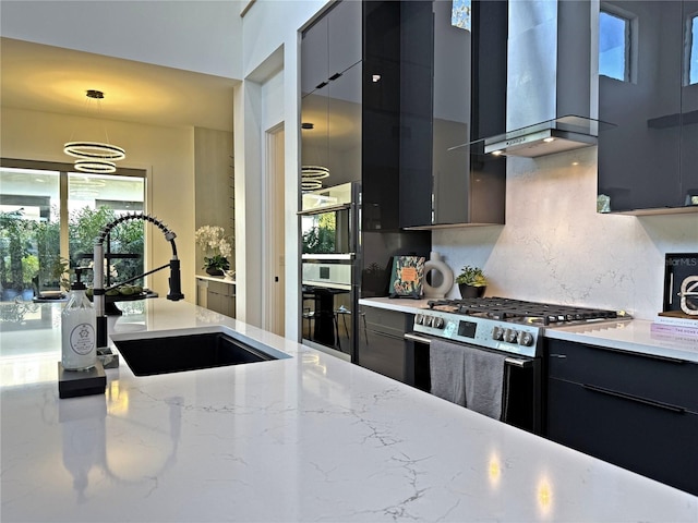 kitchen with pendant lighting, sink, stainless steel stove, wall chimney exhaust hood, and decorative backsplash