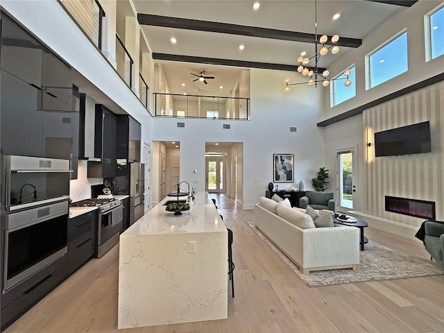 living room with light wood-type flooring, a towering ceiling, and plenty of natural light