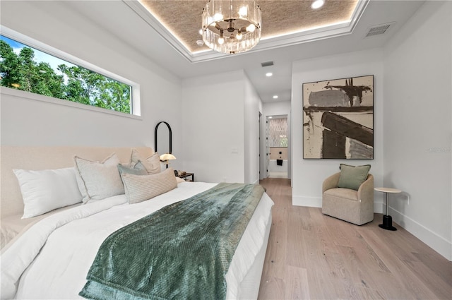 bedroom featuring a raised ceiling, light hardwood / wood-style flooring, and a notable chandelier