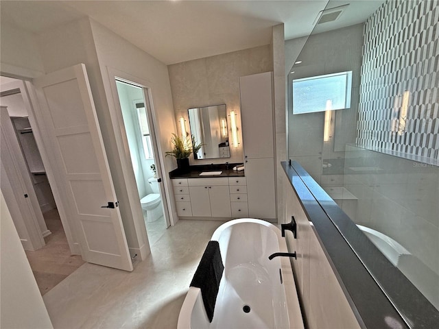 bathroom featuring a tub, vanity, tile walls, and toilet