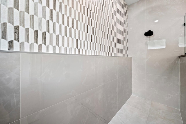 bathroom featuring a shower and tile walls