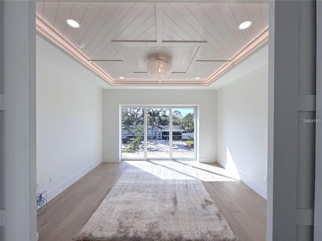 unfurnished room featuring a raised ceiling, wood ceiling, and light wood-type flooring