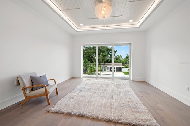 sitting room with a tray ceiling, hardwood / wood-style flooring, and wood ceiling