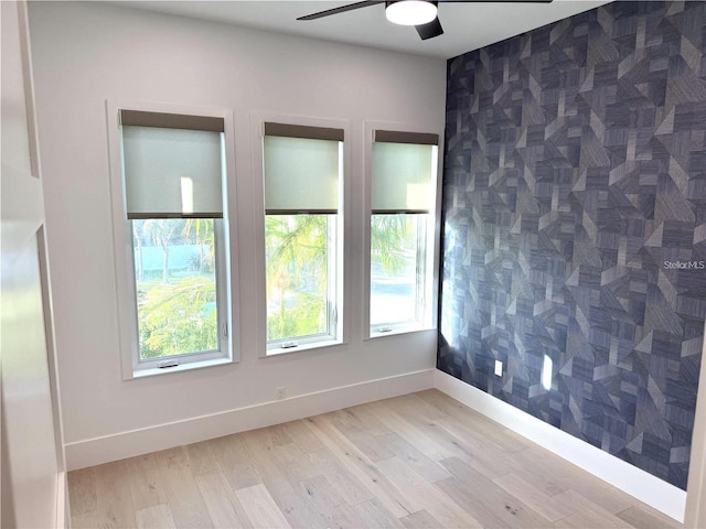 spare room featuring ceiling fan, light hardwood / wood-style floors, and tile walls